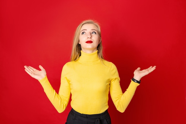 Linda mulher loira em pé sobre um fundo vermelho