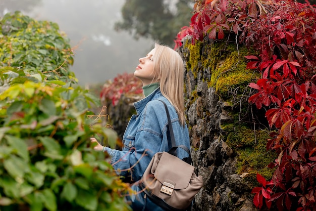 Linda mulher loira em um jardim com trepadeira da Virgínia no outono