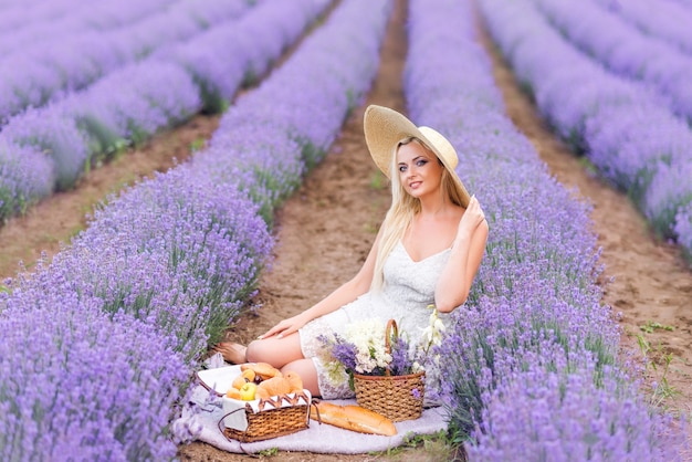 Linda mulher loira em um piquenique em um campo de lavanda.