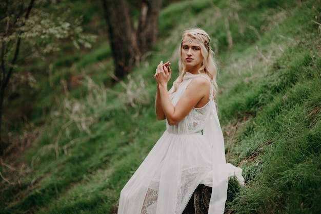 Linda mulher loira em um vestido branco na natureza