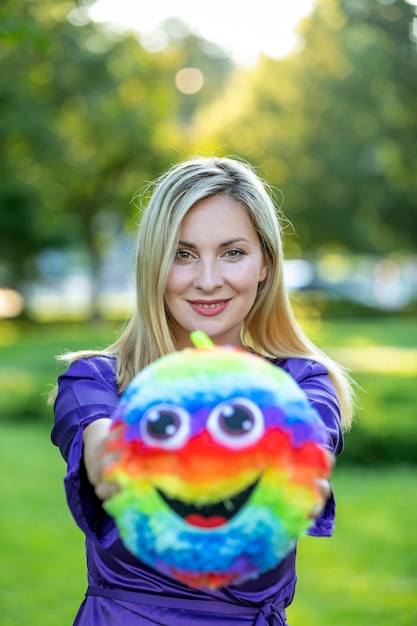 Linda mulher loira está jogando com bola colorida no parque