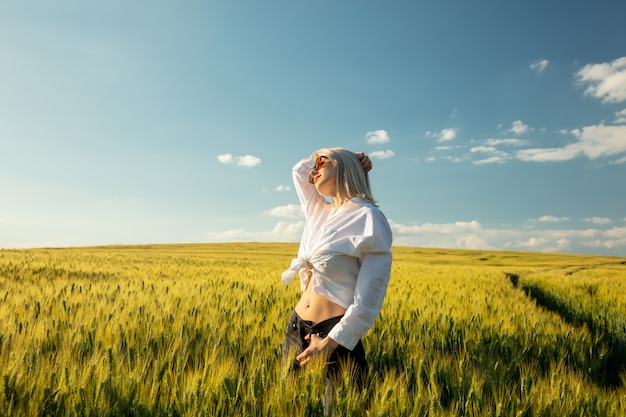 Linda mulher loira no campo de trigo na hora por do sol