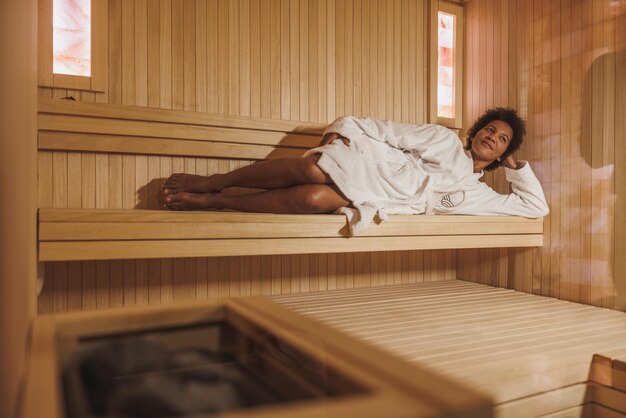 Linda mulher madura afro-americana desfrutando de uma sauna no centro de spa.