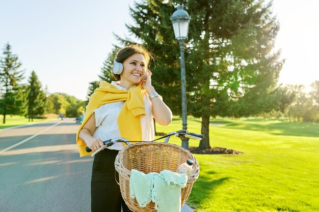 Linda mulher madura ativa com bicicleta na estrada no parque