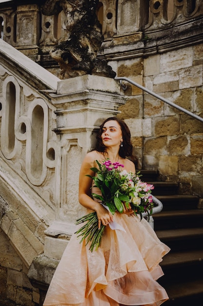 Linda mulher morena com um buquê de flores em um vestido rosa