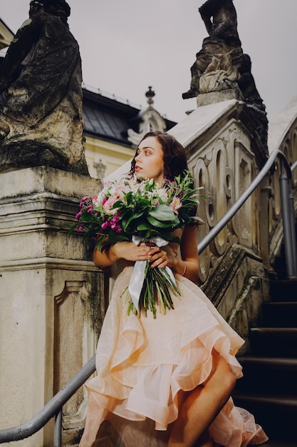 Linda mulher morena com um buquê de flores em um vestido rosa