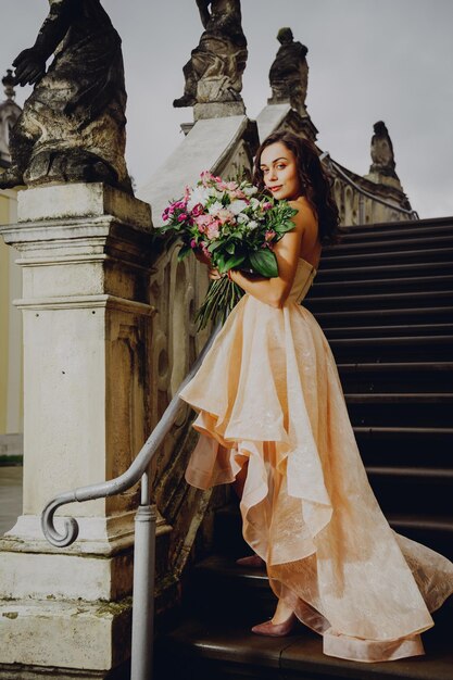 Linda mulher morena com um buquê de flores em um vestido rosa