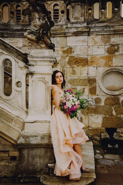 Linda mulher morena com um buquê de flores em um vestido rosa