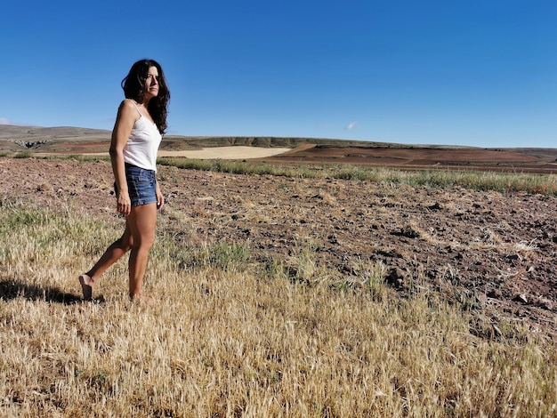 Linda mulher morena de meia idade andando no campo com os pés descalços Copie o espaço