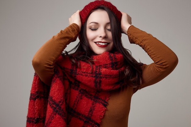 Foto linda mulher morena de suéter e chapéu vermelho com grande cachecol de malha