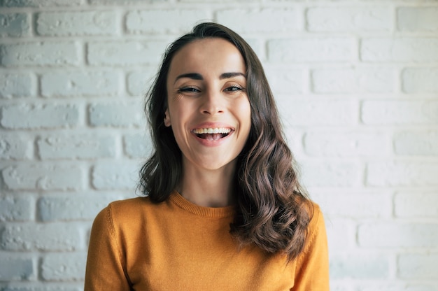 Linda mulher morena feliz e sorridente com pele, cabelo saudáveis e um sorriso vivo e cheio de dentes olhando para a câmera