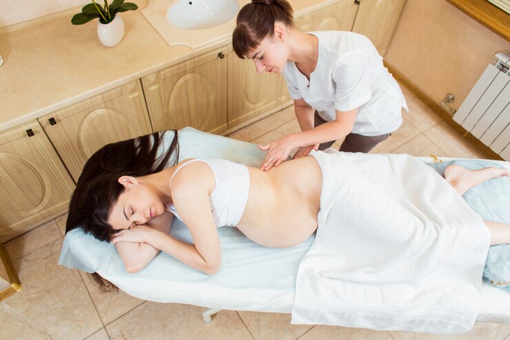 Linda mulher morena grávida com cabelos longos, desfrutando de massagem nas costas, em uma sala de esteticista