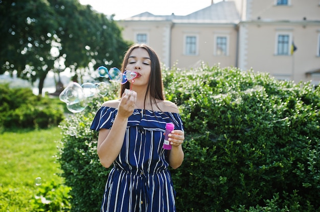 Linda mulher morena na rua da cidade deixa escapar bolhas de sabão.