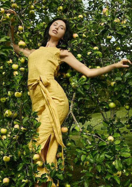 Linda mulher morena vestido amarelo moda no jardim de maçã