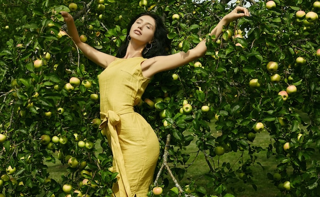 Linda mulher morena vestido amarelo moda no jardim de maçã