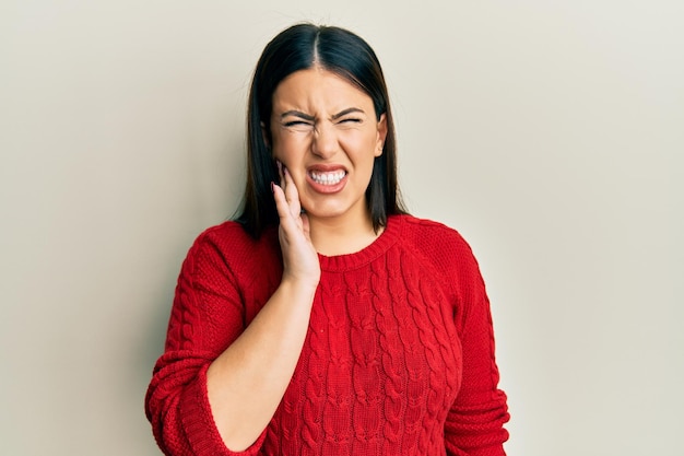 Linda mulher morena vestindo suéter de inverno de lã tocando a boca com a mão com expressão dolorosa por causa de dor de dente ou doença dentária nos dentes dentista