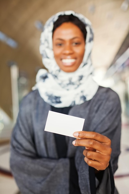 Linda mulher muçulmana africana segurando um cartão de visita em branco