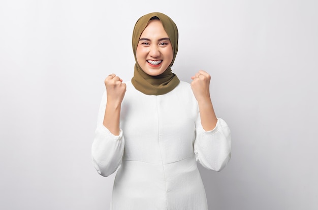 Linda mulher muçulmana asiática animada usando hijab comemorando o sucesso e olhando para a câmera isolada no fundo branco Conceito de estilo de vida religioso de pessoas
