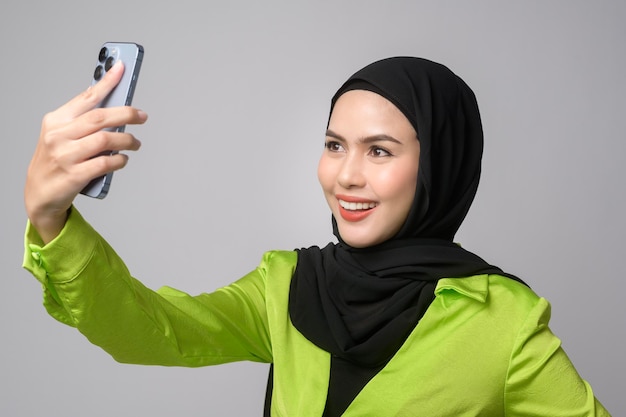 Linda mulher muçulmana com hijab usando smartphone sobre o conceito de tecnologia de fundo branco x9x9