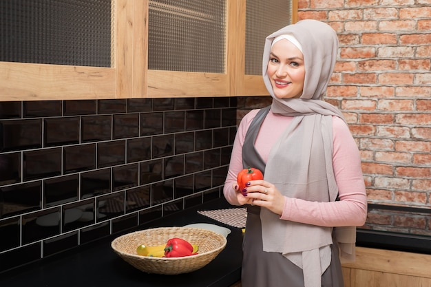 Linda mulher muçulmana com pimenta na mão no espaço da cópia da cozinha