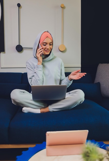 Linda mulher muçulmana de meia-idade com laptop em casa
