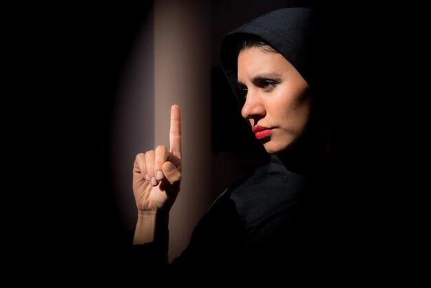 Linda mulher muçulmana no escuro com raiva parece fundo preto