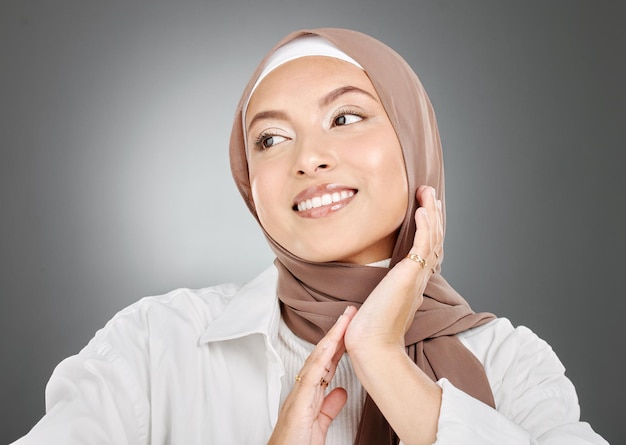 Linda mulher muçulmana posando em um estúdio usando um hijab Tiro na cabeça de um modelo árabe feliz e confiante em pé contra um fundo cinza Mulher elegante usando um lenço na cabeça