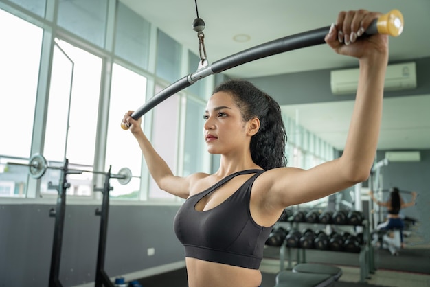 Linda mulher musculosa exercitando músculos de construção fisiculturista feminina atlética muscular puxada no simulador de esportes