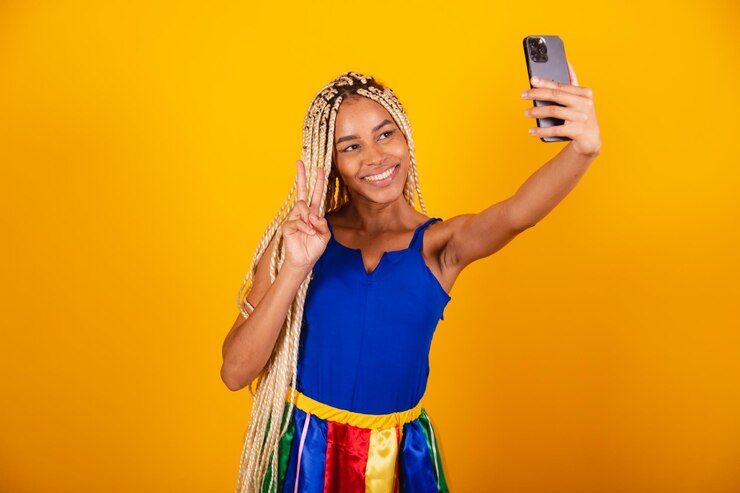 Foto linda mulher negra brasileira com tranças vestindo roupas para o carnaval segurando o auto-retrato do smartphone