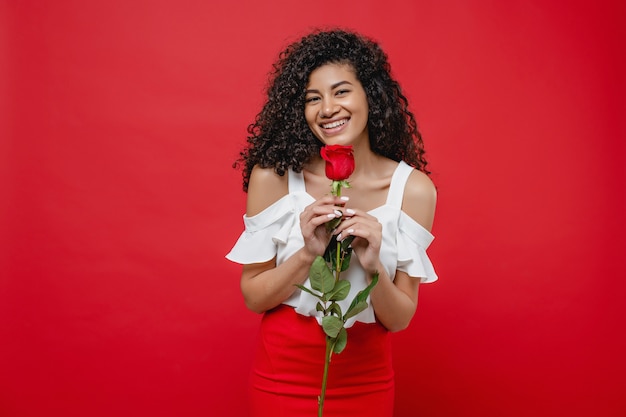 Foto linda mulher negra com rosa nas mãos isoladas sobre vermelho