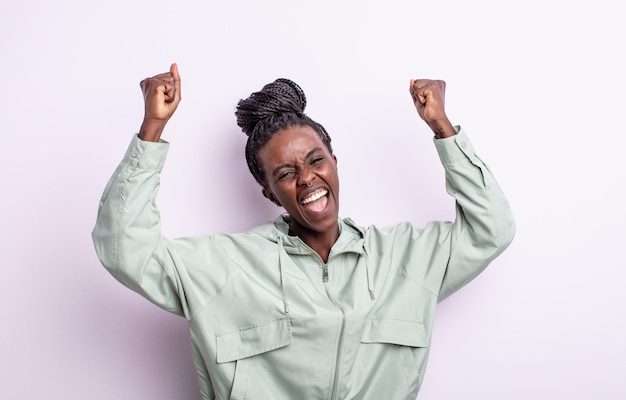 Linda mulher negra gritando triunfantemente, parecendo vencedora animada, feliz e surpresa, comemorando