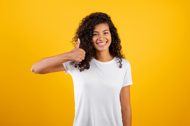 Linda mulher negra, mostrando os polegares isolados sobre amarelo