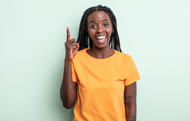 Linda mulher negra se sentindo um gênio feliz e animado depois de realizar uma ideia, levantando o dedo alegremente, eureka!