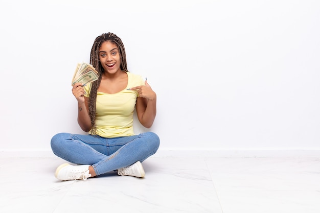 linda mulher negra sentada no chão com notas