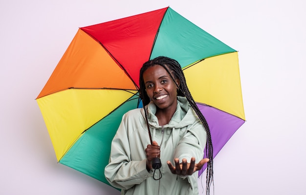 Linda mulher negra sorrindo alegremente com simpáticos e oferecendo e mostrando um conceito. conceito de guarda-chuva