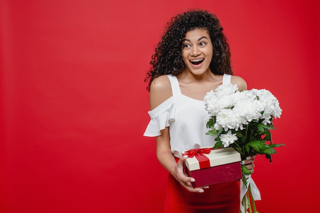 Foto linda mulher negra sorrindo com caixa de presente e buquê de flores brancas