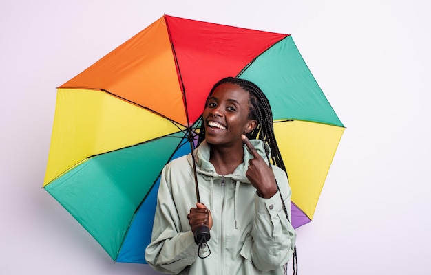 Linda mulher negra sorrindo com confiança, apontando para o próprio sorriso largo. conceito de guarda-chuva