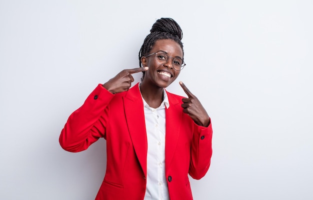 Linda mulher negra sorrindo com confiança, apontando para o próprio sorriso largo. conceito de mulher de negócios