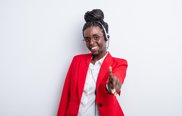 linda mulher negra sorrindo com orgulho e confiança fazendo o número um. conceito de telemarketing