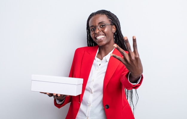 Linda mulher negra sorrindo e parecendo amigável, mostrando o número quatro. empresária com uma caixa branca