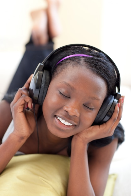 Linda mulher ouvindo música com fones de ouvido deitado em um sofá