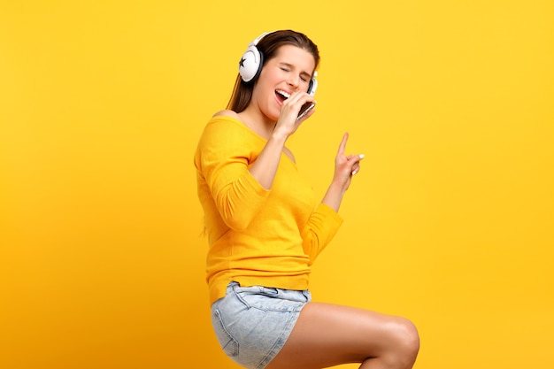 linda mulher ouvindo música no celular sobre amarelo