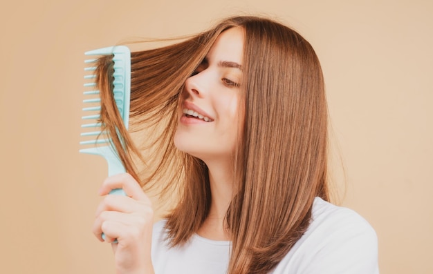 Linda mulher penteia o cabelo saudável Penteando o cabelo feminino longo e saudável de perto Atraente linda garota positiva alegre penteando o brilho do cabelo sedoso isolado