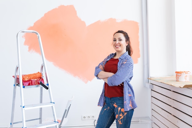 Linda mulher pintando a parede com rolo de pintura. Retrato de uma jovem mulher bonita pintando