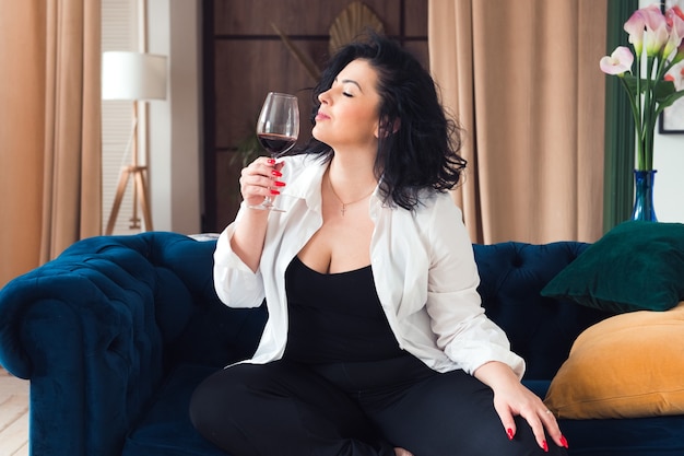 Foto linda mulher plus size relaxando com uma taça de vinho