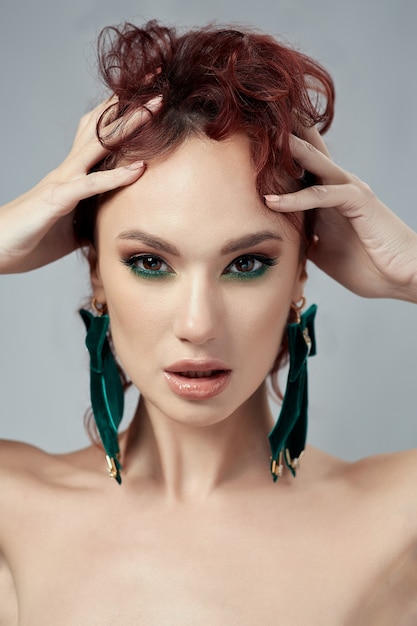 Foto linda mulher ruiva com maquiagem e brincos verdes