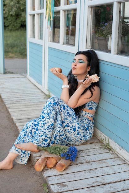 Foto linda mulher saboreando seu pão senhora retrô sentada na porta do café linda mulher comendo