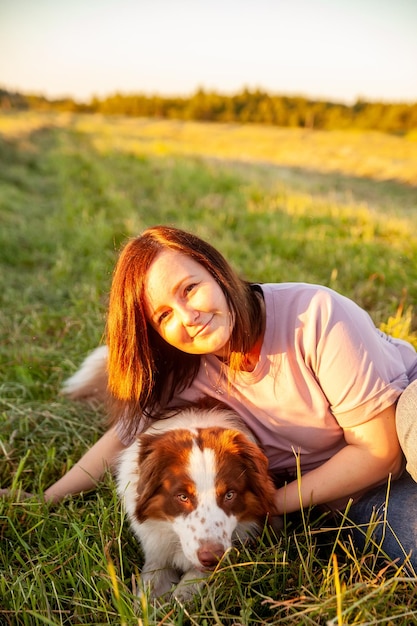 Linda mulher saindo com seu cachorro no campo por do sol