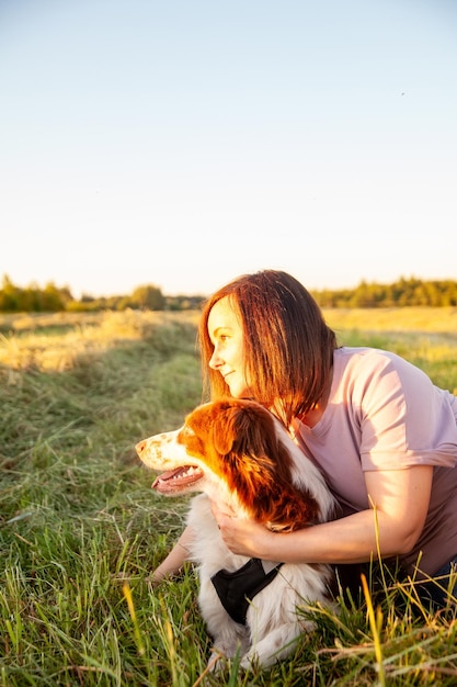 Linda mulher saindo com seu cachorro no campo por do sol