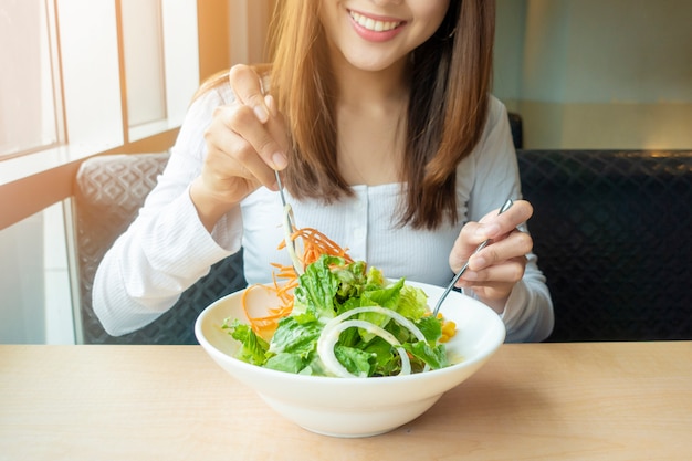 Linda mulher saudável está segurando salada de legumes